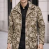 Man wearing olive and cream botanical print camouflage jacket over black shirt and trousers in urban setting